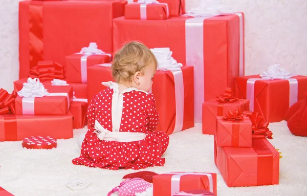 Little baby play near pile of wrapped red gift boxes. My first christmas. Sharing joy of baby first christmas with family. Baby first christmas once in lifetime event. Gifts for child first christmas