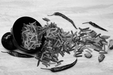 Yemek pişirme malzemeleri ve siyah seramik tabakta İtalyan makarnası.