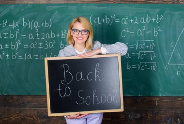 Öğretmen kadın okula geri tahta yazıt tutun. Yine okul zamanı. Okul öğretmeni öğrencileri ağırlamadan memnun. Okul yılına başla. Öğrencileri schoo'ya geri kabul etmenin en iyi yolları