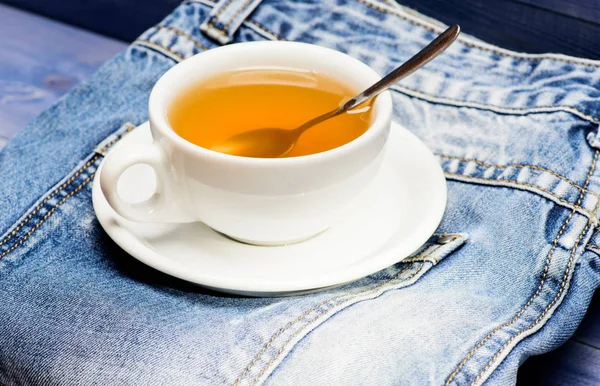 Healthy habits. Tea time concept. Cup mug hot water and bag of tea. Process tea brewing in ceramic mug. Herbal green or black whole leaf. Mug filled boiling water and tea bag on blue jeans background