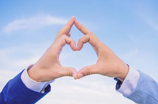 Hands put together in heart shape blue sky background. Love symbol concept. Male hands in heart shape gesture symbol of love and romance. Hand heart gesture forms shape using fingers