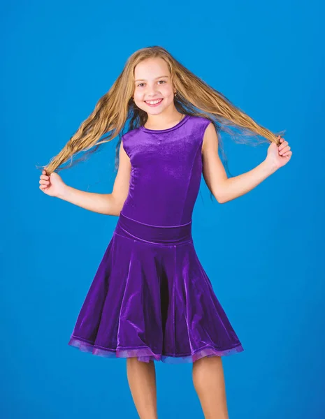 Kid girl with long hair wear dress on blue background. Hairstyle for dancer. How to make tidy hairstyle for kid. Things you need know about ballroom dance hairstyle. Ballroom latin dance hairstyles