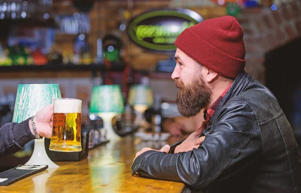 Man with beard spend leisure in dark bar. Brutal lonely hipster. Brutal hipster bearded man sit at bar counter. Friday evening. Bar is relaxing place to have drink and relax. Hipster relaxing at bar