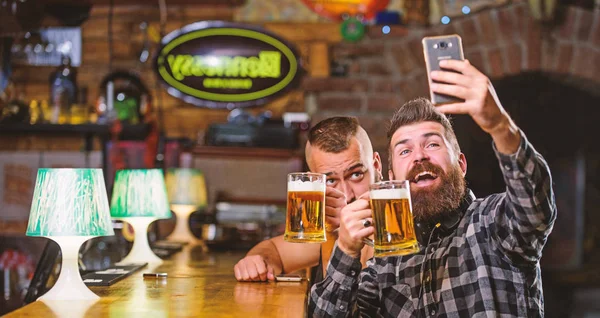 Alarak selfie kavramı. Selfie arkadaşlar sosyal ağlara göndermek. Adam bar bira içiyor. Harika akşam barda hatırlamak selfie fotoğraf çekmek. Çevrimiçi iletişim. Adam hipster tutun smartphone sakallı — Stok fotoğraf
