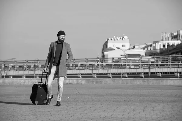 Business trip. Man bearded hipster travel with big luggage bag on wheels. Let travel begin. Traveler with suitcase arrive to airport railway station. Hipster ready enjoy travel. Carry travel bag