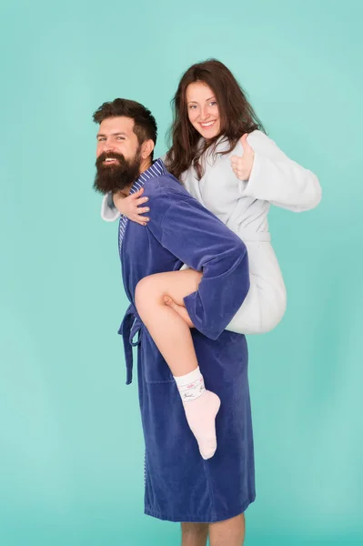 Trust and support. True love. Lets stay at home. They are closest people. Support in any time. Reliable support. Handsome young man piggybacking beautiful woman. Couple in bathrobes having fun