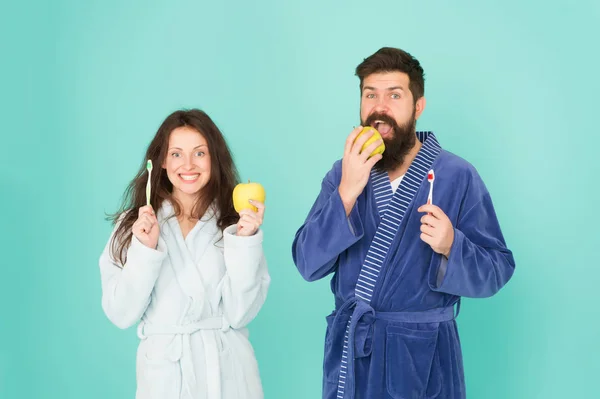 Healthy habits. Brush teeth every morning. Oral hygiene. Couple bathrobes hold toothbrushes and apples. Personal hygiene. Couple in love cleaning teeth. Freshness and cleanliness. Keep teeth healthy