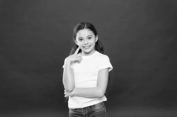 Regard réfléchi du modèle de soins de la peau. Petite fille gardant le doigt sur la peau des joues. Adorable petite fille sans maquillage. Cosmétiques de beauté pour enfants. Le soin parfait du visage et des soins de la peau. Elle est mignonne. — Photo