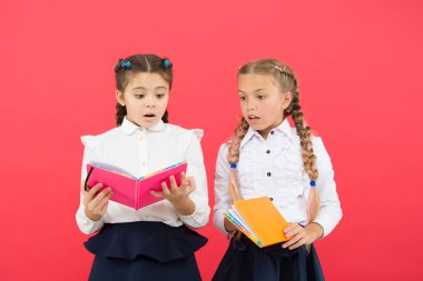 Okumak kapıları açar. Kırmızı arka plan üzerine kitap okuyan küçük çocuklar. Sevimli küçük kızlar okulda okumayı öğrenirler. Sevimli öğrenciler önemli bilgileri öğrenmek için okuma