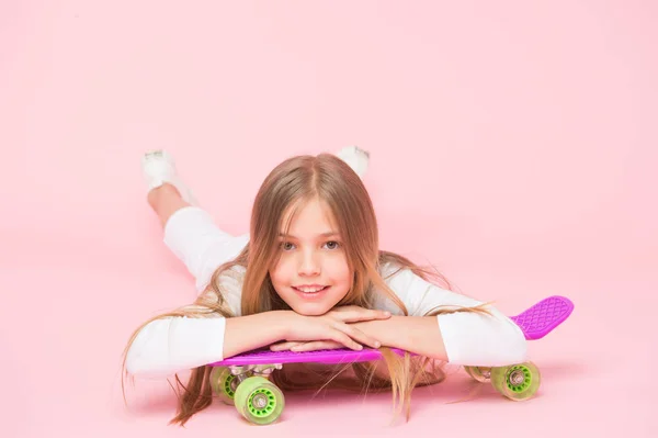 スケートボードはヒップスターを作成しました。ヒップスタースタイルとルックで微笑む愛らしい小さなスケーター。ピンクの背景にスケートボードでリラックスかわいいヒップスター。バイオレットペニーボードとハッピーヒップスター — ストック写真