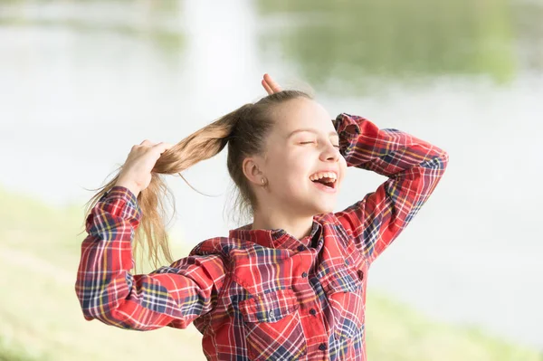 Sê feliz e sorri. Menina feliz gosta de fazer seu cabelo no dia de verão. Criança pequena adorável com cabelo loiro longo e sorriso feliz. Feliz dia internacional das crianças — Fotografia de Stock