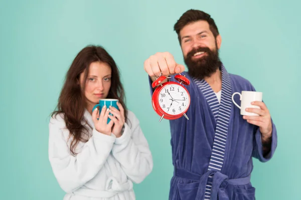 Guy in bath clothes hold tea coffee. Breakfast concept. Every morning begins with coffee. Couple in bathrobes with mugs. Its coffee time. Man with beard and sleepy woman enjoy morning coffee or tea