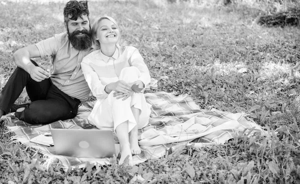 Coppia uomo barbuto e donna bionda rilassare la natura mentre sedersi sul prato verde erba. Relax e ispirazione concetto. Coppia con laptop relax ambiente naturale. Famiglia godere di relax natura sfondo — Foto Stock