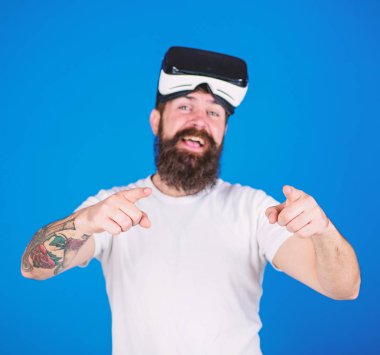 Sakal ve bıyık Vr gözlük, mavi arka plan ile olan adam. VR teknolojisi kavramı. Adam Vr gözlük veya baş ile ekran monte. Hipster ileri işaret parmağı ile işaret mutlu yüz