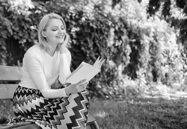 Girl keen on book keep reading. Reading literature as hobby. Woman blonde take break relaxing in park reading book. Girl sit bench relaxing with book, green nature background. Books are her passion