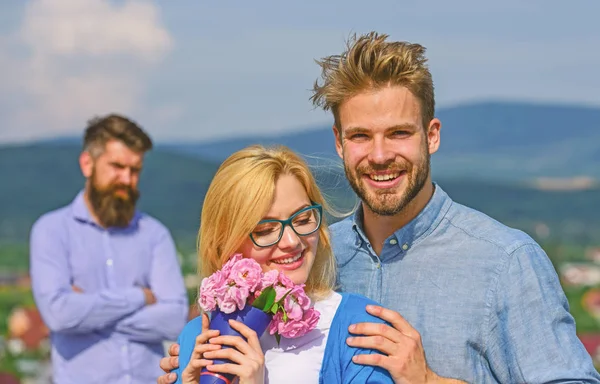 Pareja enamorada citas mientras celoso barbudo hombre viendo esposa engañándolo con amante. Los amantes abrazos al aire libre coquetear relaciones románticas. Pareja romántica pareja amantes flores ramo. Concepto de infidelidad —  Fotos de Stock