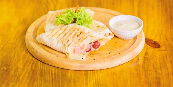 Κρέας τυλιγμένο με lavash burrito. Παραδοσιακή κουζίνα γεύμα εστιατόριο. Burrito τορτίγια σερβίρεται ξύλινη σανίδα. Το εστιατόριο έννοια των τροφίμων. Lavash burrito γεμιστό λουκάνικο και τυρί σάλτσα κρέατος σερβίρεται σαλάτα — Φωτογραφία Αρχείου