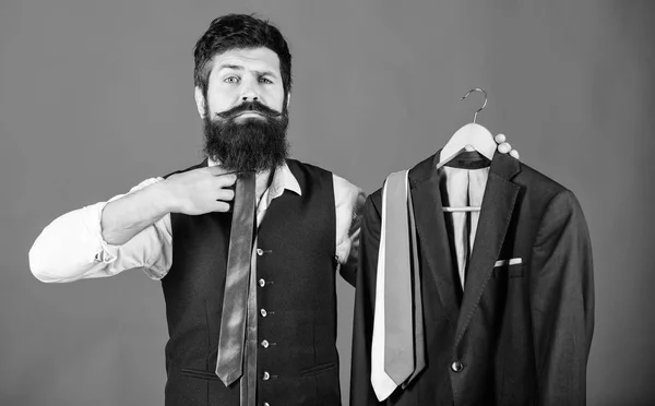 Cool fashion accessory to his ensemble. Businessman matching necktie to his cool look. Bearded man holding cool classy neckties and suit jacket. Creating a cool business dress code