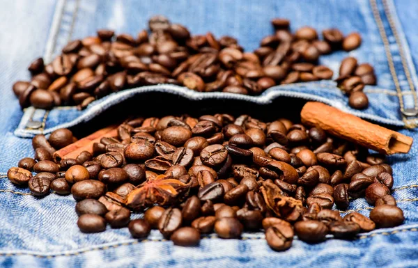 Coffee for inspiration and energy charge. Coffee shop or store. Texture and background concept. Fresh roasted coffee close up. Beans and spices in jeans pocket. Degree of roasting coffee beans