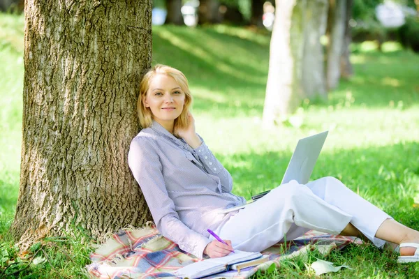 Nő a laptop számítógép munka szabadban sovány a fa törzs. Lány dolgozik laptop parkban ülni füvet. Oktatási technológia és Internet-koncepció. Természeti környezet iroda. Munka a szabadban ellátások — Stock Fotó