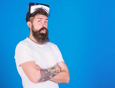 Sakal ve bıyık Vr gözlük, mavi arka plan ile olan adam. Adam Vr gözlük veya baş ile ekran monte. Hipster sürpriz yüzündeki göğsüne, kopya alanı geçti ellerini tutar. VR teknolojisi kavramı