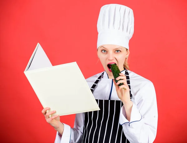 Hungrig. Restaurangens meny. Kulinariska bantning. Hemmafru med Kok bok. professionell i köket äter gurka. Rätter. kvinna i hatt och förkläde. lycklig kvinna matlagning hälsosam mat genom recept — Stockfoto