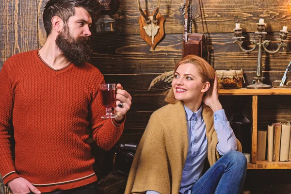 Pareja pasar la noche agradable, fondo interior. Mujer y hombre en caras sonrientes disfrutar de un ambiente acogedor con bebidas calientes. Concepto de comodidad. Familia, pareja enamorada disfrutar de vacaciones en casa de guardabosques — Foto de Stock