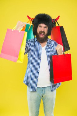 Alışveriş şampiyonu. Boğa boynuzları şapkalı mutlu hipster başarılı alışveriş sonrası paperbags Limited tutarak. Sakallı adam alışveriş çantaları ile gülümsüyor. Alışveriş onun bağımlılığı.