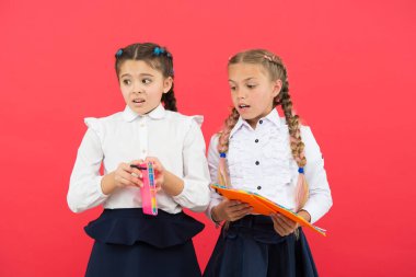 Çocukların okul üniformaları kitabını tutuyor. Kırtasiyeye takıntısı olan kızlar. Okul kızı şov günlüğü defteri. Okul malzemeleri konsepti. Okul kırtasiyesi. Ders çalışmak için şirin kırtasiye malzemeleri al.