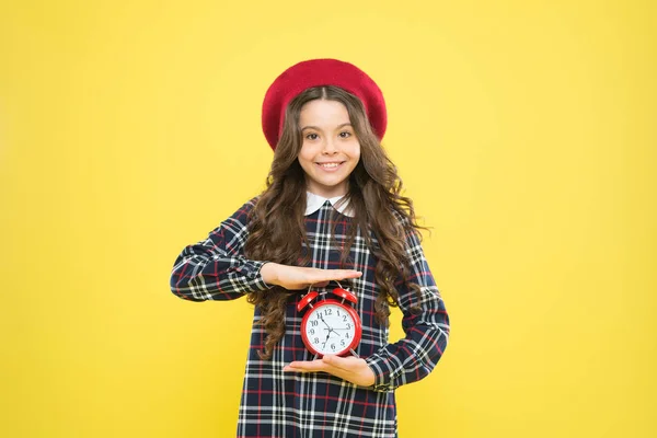 Buenos días. Niño pequeño sonriendo por la mañana sobre fondo amarillo. Feliz niña sosteniendo el despertador temprano en la mañana. Despertar por la mañana — Foto de Stock