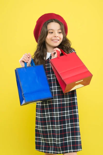 Descuento. Niña en sombrero de estilo francés. chica feliz con el pelo largo en boina. pequeño adicto a las compras de belleza. Regalo de vacaciones. De compras. niño con bolsa de compras. niño parisino en amarillo. concepto de descuento —  Fotos de Stock