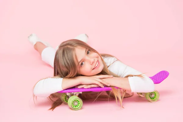 ペニーボードと幸せな振動を広める。ピンクの背景にペニーボードデッキでリラックス小さな女の子スケーター。紫のペニーボードで微笑んで小さな子供。ペニースケートボードと幸せなヒップスター — ストック写真