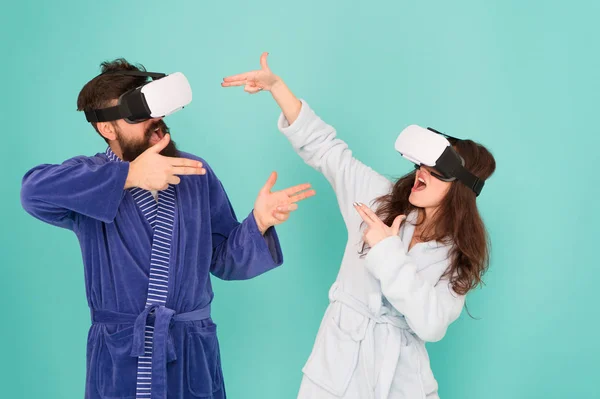 Manos arriba. Párate y entrega. Tecnología VR y futuro. Emocionantes impresiones. Pareja en albornoces usan gafas VR. Juegos y entretenimiento. Hombre y mujer exploran la realidad virtual en casa. Comunicación VR — Foto de Stock