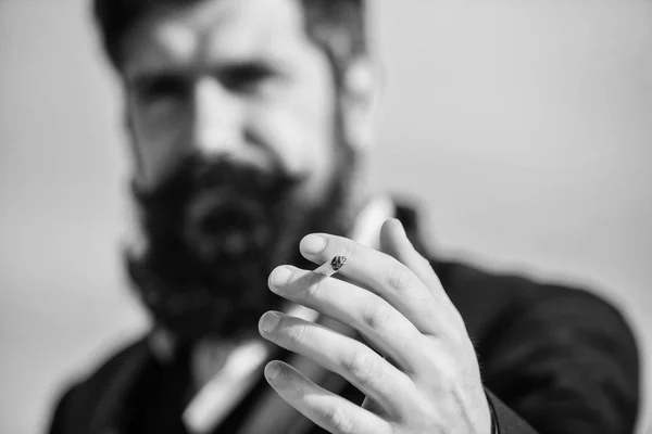 Cigarettes help us with everything from boredom to anger management. Bearded hipster smoking cigarette sky background. Guy cigarette enjoy nicotine influence. Man with beard mustache hold cigarette — Stock Photo, Image