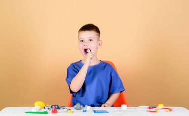 Çocuk sevimli çocuk gelecek Doktor kariyer. Sağlıklı bir hayat. Çocuk küçük doktor stetoskop ve tıbbi aletler ile masaya oturur. Tıp konsepti. Sağlık. Tıbbi muayene. Tıp eğitimi. Oyun oyna