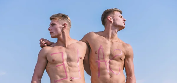 Hommes musclé avec torse sexy nu, ciel sur fond. Les athlètes sur les visages sérieux étreignent et regarde les côtés opposés. Concept de vente. Athlètes avec inscription vente sur des coffres musculaires sexy — Photo