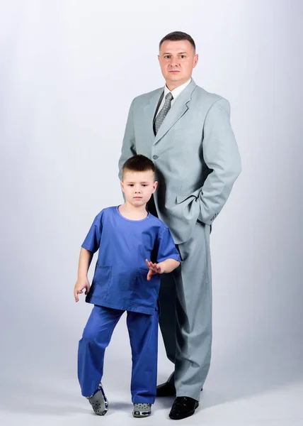Respectable profession. Man respectable businessman and little kid doctor uniform. Family business. Doctor respectable career. Dad boss. Father and cute small son. Child care development upbringing
