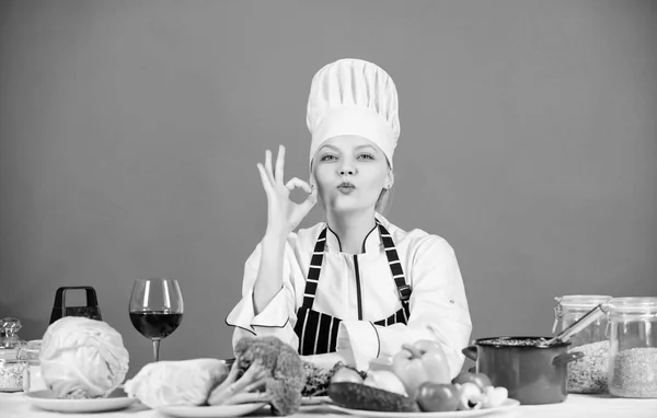 Kız sevimli şef mutfak öğretmek. Evde denemek için en iyi mutfak tarifleri. Mükemmel bir tarif. Malzemeleri lezzetli bir öğüne dönüştürün. Mutfak becerileri. Kadın şef masa malzemeleri yakınında şapka önlük giymek — Stok fotoğraf
