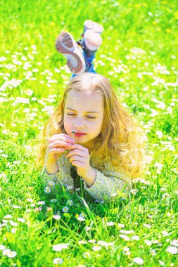 Çimen, grassplot arka plan üzerinde yatan kız. Duyarlılık kavramı. Çocuk ihale papatya çiçekleri ile çayır yalan ise bahar güneşli hava keyfini çıkarın. Papatya çiçek kız sakin yüz tutan