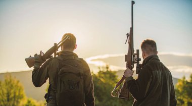 Avcılar arkadaşlar eğlence keyfini çıkarın. Avcılar arkadaşlar gamekeepers silahlı gökyüzü arka plan siluet. Avcı tüfekler doğa ortamı. Bu harika bir gündü. Av sezonu bitirmek. Dağlarda günbatımı keyfini çıkarın