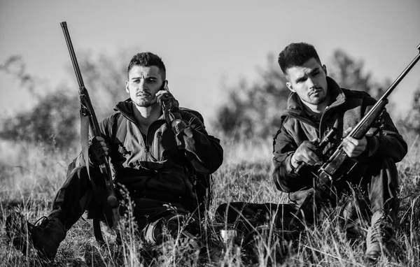 El descanso para los hombres de verdad concepto. Cazadores con rifles relajantes en ambiente natural. Caza con amigos ocio hobby. Cazadores satisfechos con la bebida de calentamiento de captura. Cazadores amigos disfrutar del ocio —  Fotos de Stock