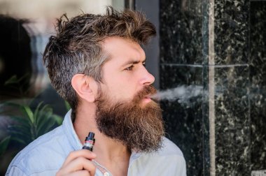 Sakallı vahşi erkek elektronik sigara içiyor. Sakallı olgun hipster. hipster adam vaping cihazı tutun. adam sigara ecigarette. Sağlık güvenliği ve bağımlılık. buharı teneffüs. Sigara yakıyor