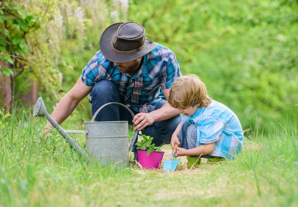 Make planet greener. Growing plants. Take care of plants. Day of earth. Boy and father in nature. Gardening tools. Planting flowers. Dad teaching little son care plants. Little helper in garden