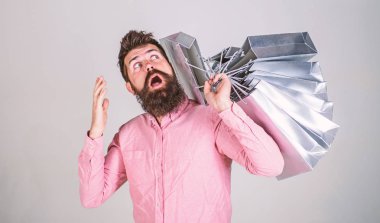 Satış ve indirim kavramı. Alışveriş satış sezonu, torba merak adam. Hipster sürpriz yüzündeki Alışverişkoliğin bağımlısı. Sakal ve bıyık taşır grup alışveriş torbaları, gri arka plan ile adam