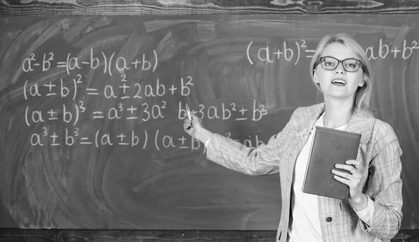 Inteligentne kobiety nauczyciel z książki wyjaśnić temat w pobliżu chalkboard. Nauczyciel w szkole wyjaśnić rzeczy i uczynić przedmiotem, ciekawe. Skomplikowane wielopłaszczyznowe działalności dydaktycznej. Co sprawia, że wielkim nauczycielem — Zdjęcie stockowe