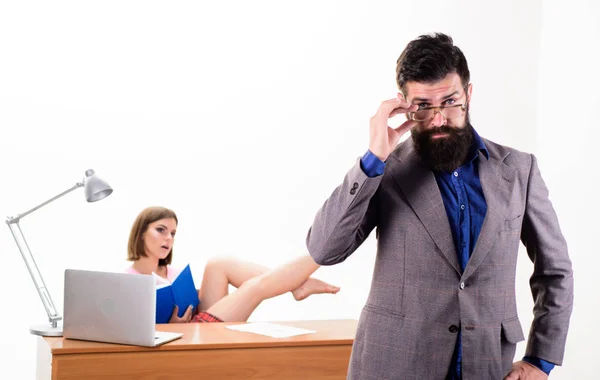 Experienced and skilled. Executive coach fixing his glasses while sexy woman working in background. Business coach with smart look and sexi employee. Smart career coach and pretty secretary in office