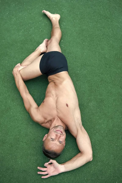 Man yoga praktijk vormen groene oppervlakte bovenaanzicht. Atleet doen yoga asana op groene achtergrond. Het beoefenen van asana concept. Guy gespierde flexibele body. Opleiding flexibiliteit rekken spieren en gewrichten — Stockfoto