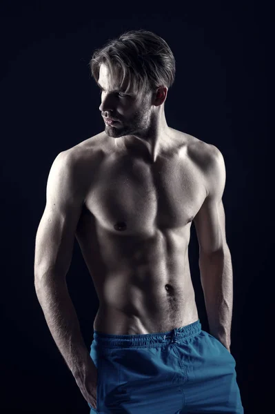 Мужчина спортсмен показывает мускулистое туловище в синих шортах — стоковое фото
