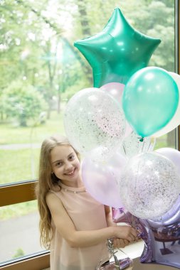 Balonlar ve doğum günü melodileri. Mutlu sevimli küçük kız parti balonları ile tatil kutluyor. Hava balonları demet ile gülümseyen sevimli küçük çocuk. Helyum balonları vesilesiyle yükselişi yapar
