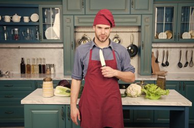 Adam şef mutfakta yemek önlük giymek. Adam kullanım keskin seramik bıçak. Keskin bıçak profesyonel bir araçtır. Şef profesyonel araçlar seçin. Mutfak aletleri ve araçları. Şef bıçak aracını pişirmeye hazır tutun